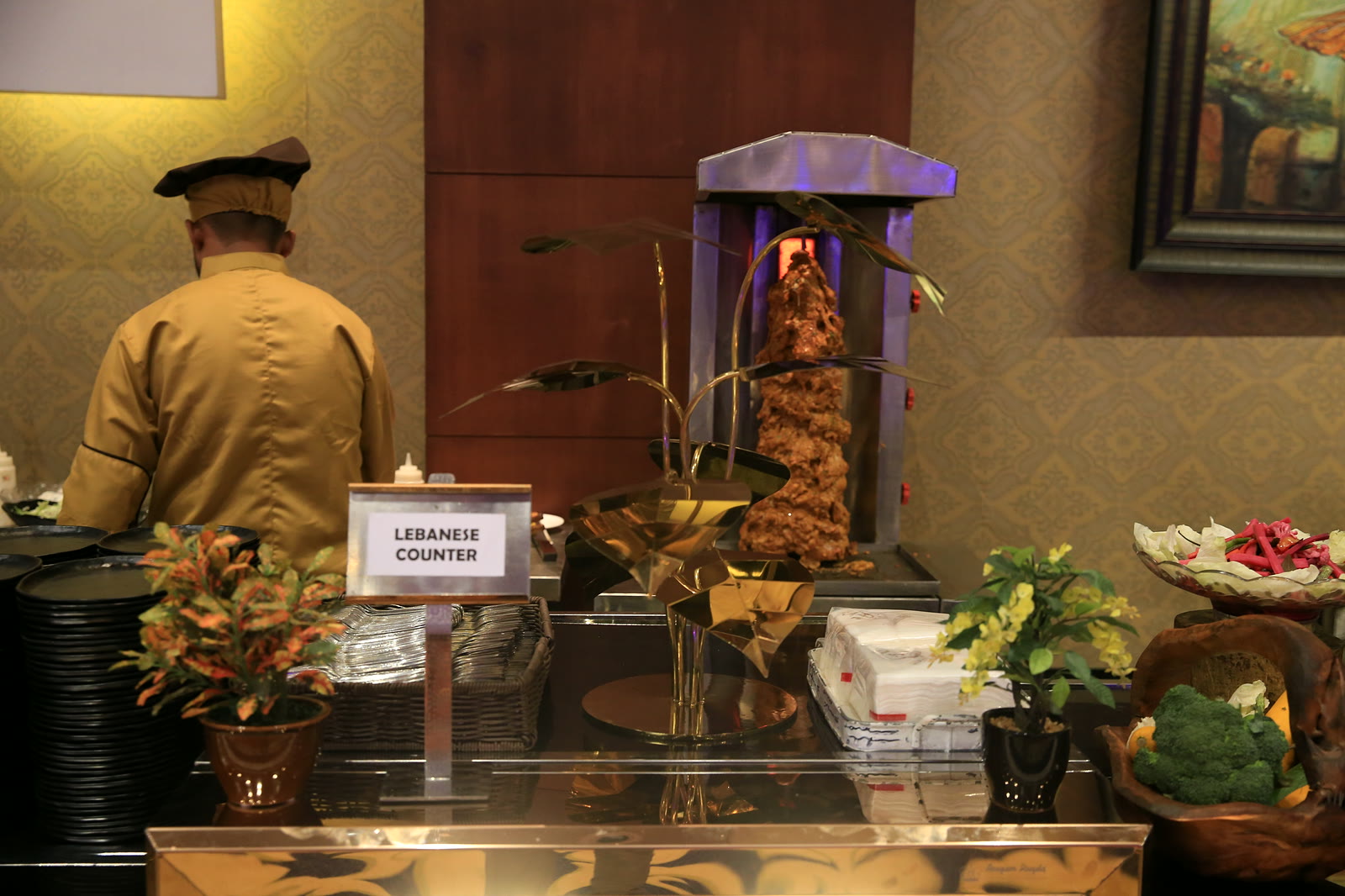 A chef at the Lebanese counter beside a turning shawarma spit
