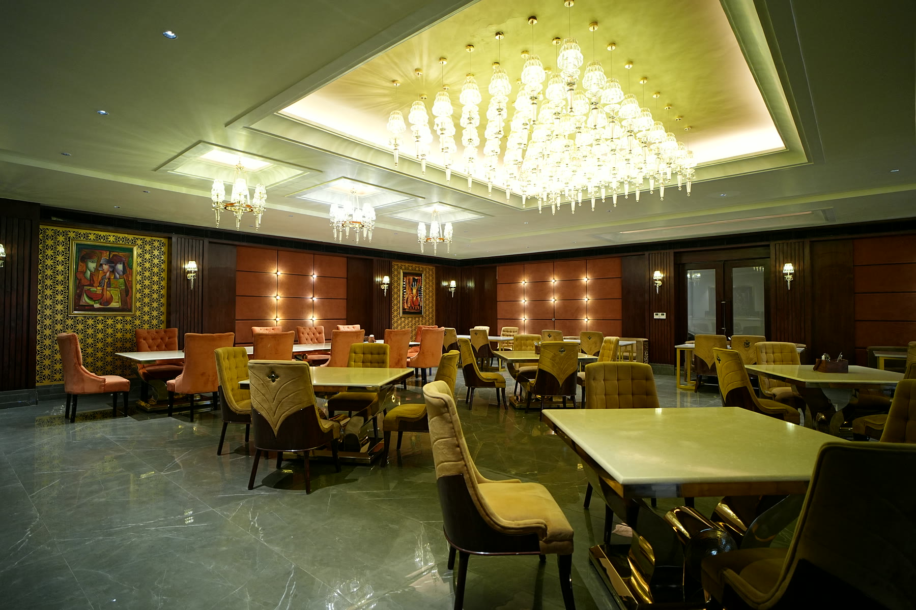 Krystal Lounge: a crystal chandelier over tables with mustard and coral velvet chairs