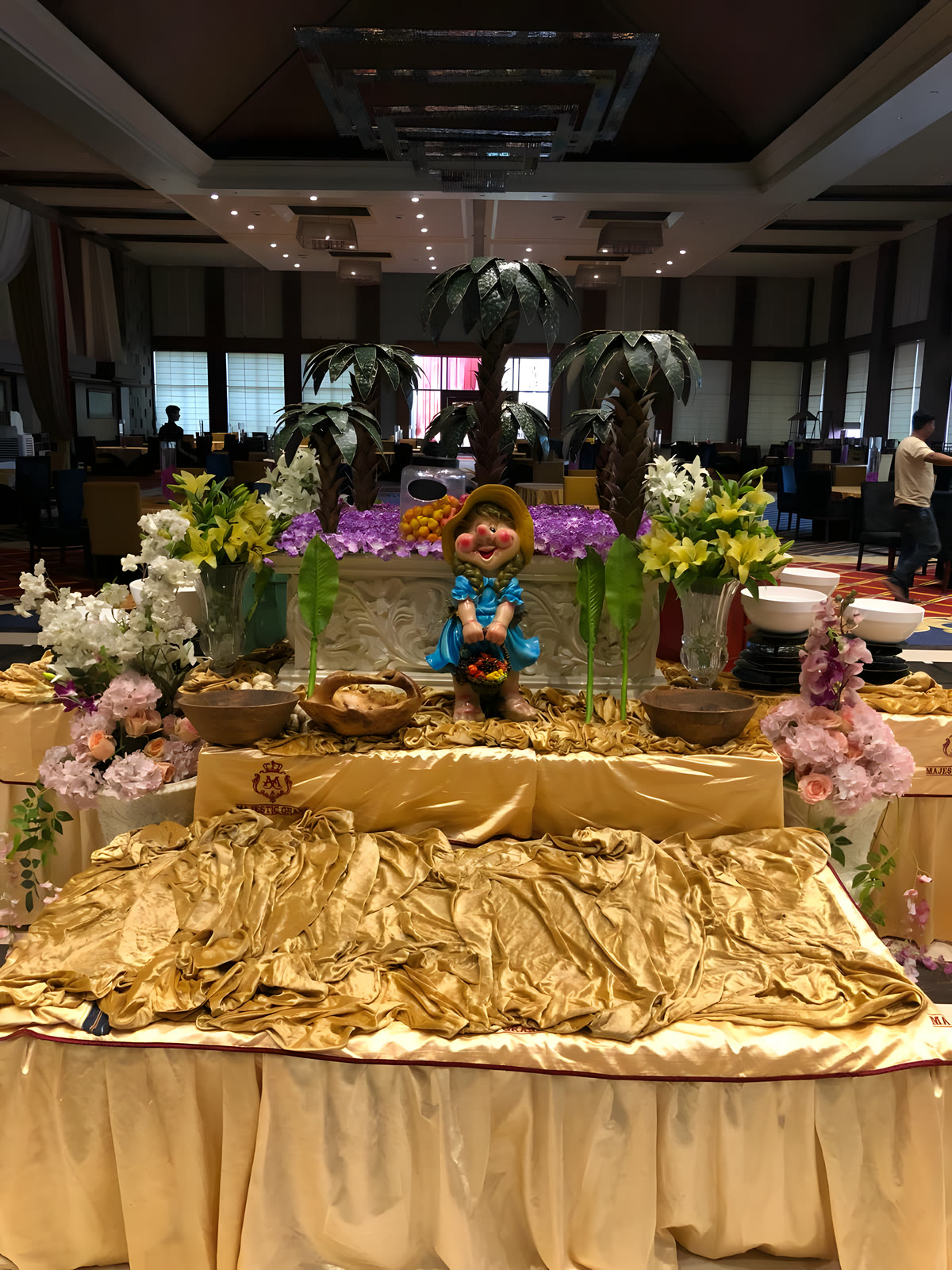 A buffet counter dressed with gold cloth and fresh flowers